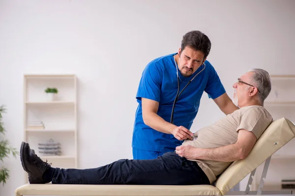 Vecchio paziente maschio visting giovane medico maschio — Foto Stock