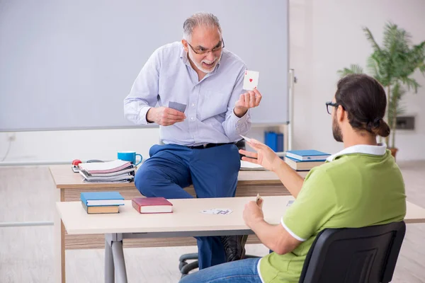 Starý muž učitel a mladý muž student hrací karty v clas — Stock fotografie