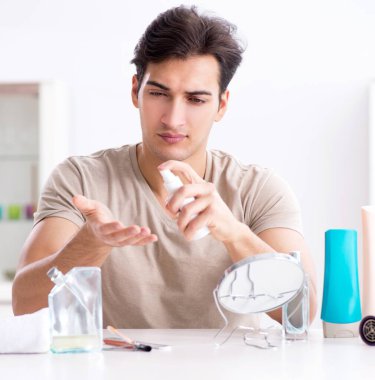 Genç yakışıklı adam aynaya bakıyor.