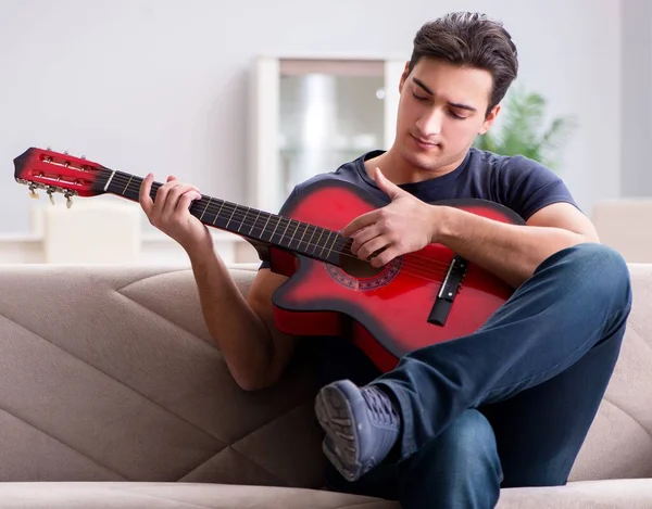 Giovane uomo che pratica la chitarra a casa — Foto Stock