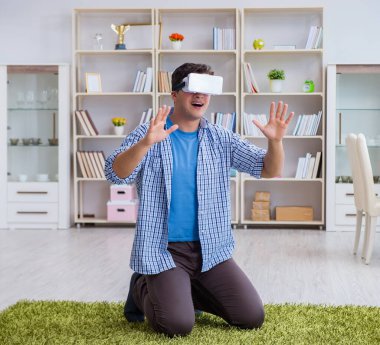 Evde sanal gerçeklik gözlüklü bir adam oynuyor.