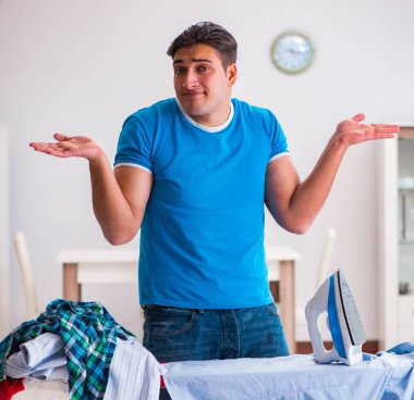 Erkek koca evde ütü yapıyor, karısına yardım ediyor.