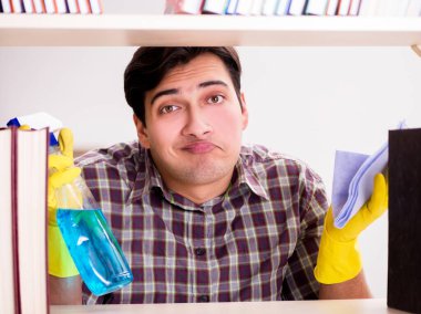 Kitaplıktaki tozları temizleyen adam