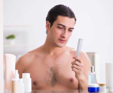 Genç adam banyoda çalışmak için hazırlanıyor.