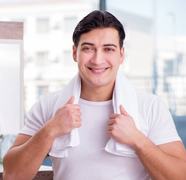 Genç yakışıklı adam yüz kremi sürüyor.