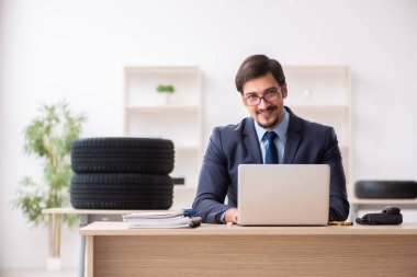 Genç adam ofiste lastik satıyor.