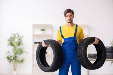 Atölyede lastiği olan genç bir erkek tamirci.