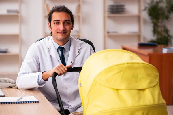 Genç erkek doktor klinikte yeni doğan bebeğe bakıyor. — Stok fotoğraf