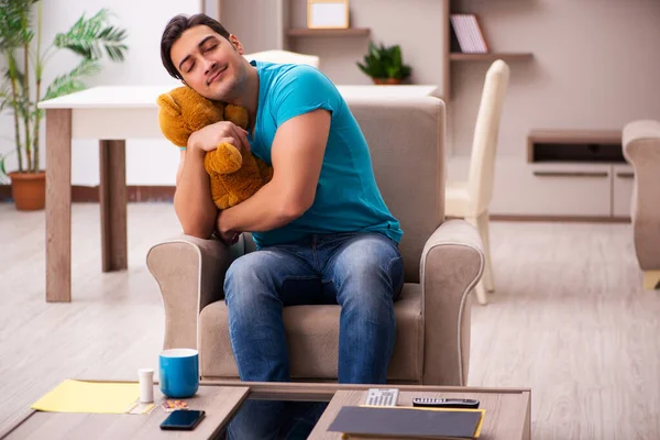 Jovem sentado com urso brinquedo em casa — Fotografia de Stock