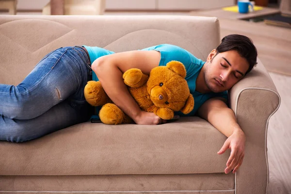 Jeune homme assis avec jouet ours à la maison — Photo