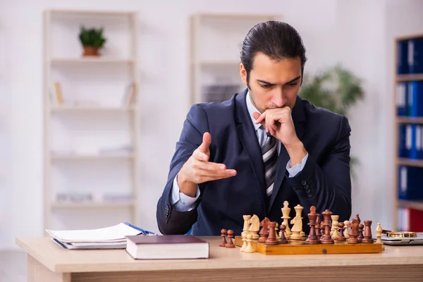 Joven empleado masculino jugando ajedrez en el lugar de trabajo — Foto de Stock