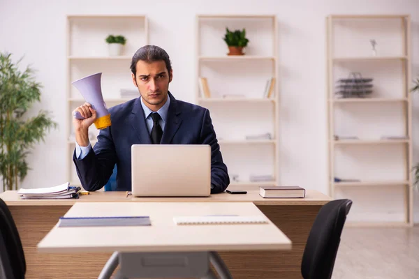 Fiatal férfi munkáltató kezében megafon az irodában — Stock Fotó