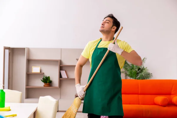 Jovem empreiteiro limpando a casa dentro de casa — Fotografia de Stock