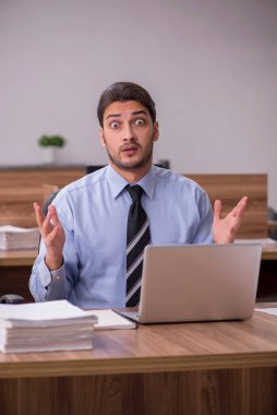 Genç bir erkek çalışan ve ofiste çok fazla iş var.