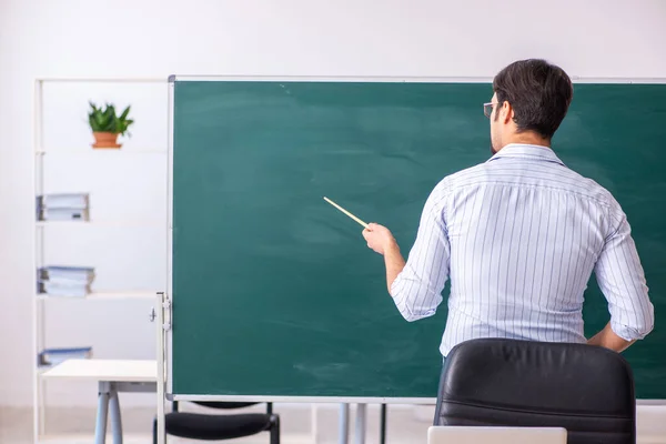 Young male teacher in front of blackboard — Stock Photo, Image