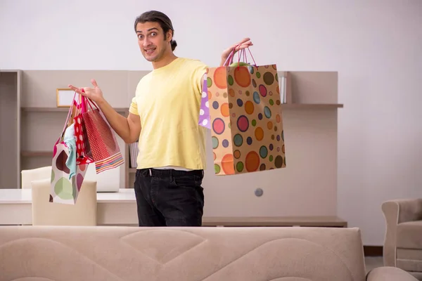 Giovane uomo con molte borse nel concetto di Natale a casa — Foto Stock