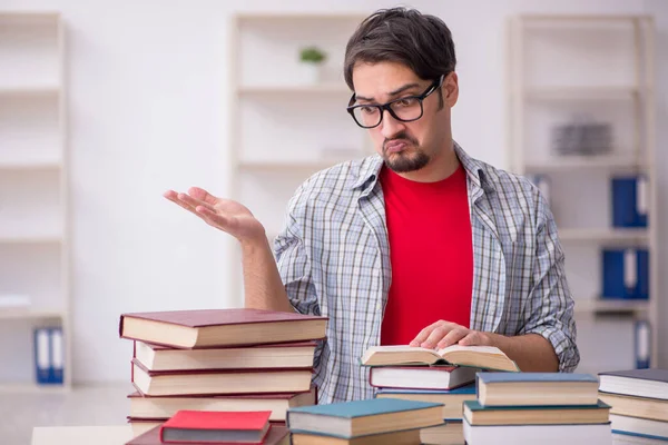 Giovane studente maschio e troppi libri in classe — Foto Stock