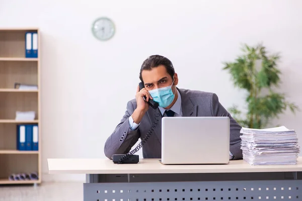 Jovem funcionário do sexo masculino usando máscara durante pandemia — Fotografia de Stock