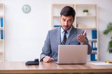 Genç yakışıklı işadamı ofiste çalışıyor.