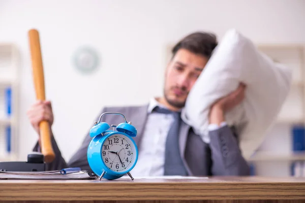 Jonge mannelijke werknemer in overslapen concept — Stockfoto