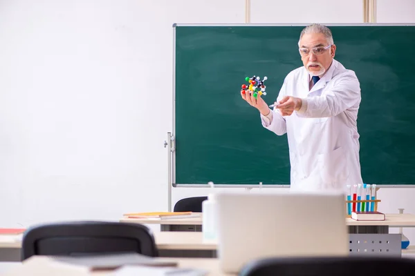 Old male teacher chemist in the classroom