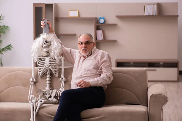 Oude man zittend op de bank met het vrouwelijke skelet — Stockfoto