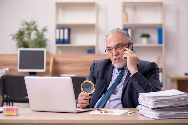 Starý muž zaměstnanec auditor držení loupe na pracovišti — Stock fotografie