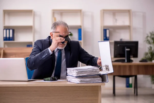 Stary audytor męski zatrudniający pracowników trzymający lornetkę w miejscu pracy — Zdjęcie stockowe