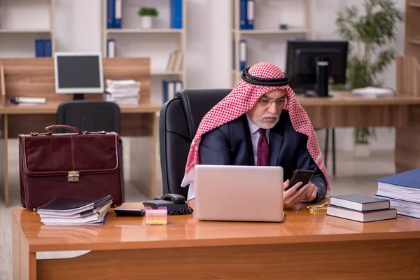 Elöregedett arab üzletember alkalmazott, aki a munkahelyén ül — Stock Fotó