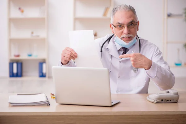 Gammal manlig läkare som arbetar på kliniken under pandemin — Stockfoto