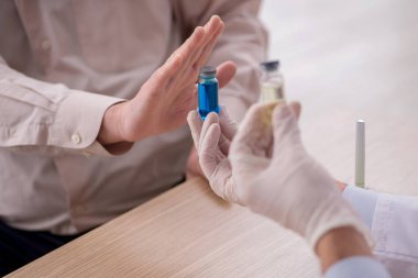 Yaşlı bir erkek hasta aşıyla genç bir doktoru ziyaret ediyor.