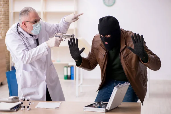 Homem mascarado ladrão roubando vacina do velho médico — Fotografia de Stock