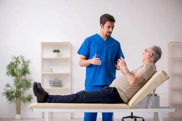 Vecchio paziente maschio visting giovane medico maschio — Foto Stock