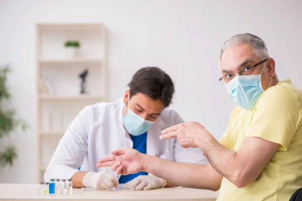 Yaşlı erkek hasta aşılama bölümünde genç bir erkek doktor. — Stok fotoğraf