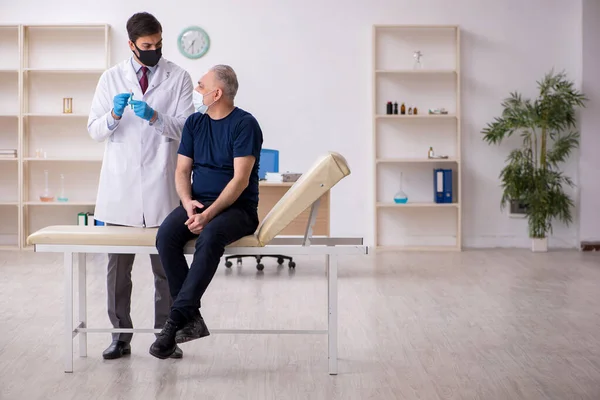 Vecchio paziente di sesso maschile in visita giovane medico di sesso maschile in conce vaccinazione — Foto Stock