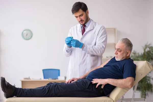 Vecchio paziente di sesso maschile in visita giovane medico di sesso maschile in conce vaccinazione — Foto Stock