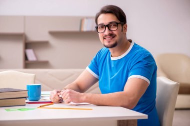 Evde okuyan genç bir erkek öğrenci.