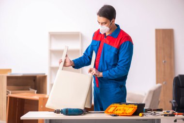 Genç erkek marangoz salgın sırasında ofiste çalışıyor.