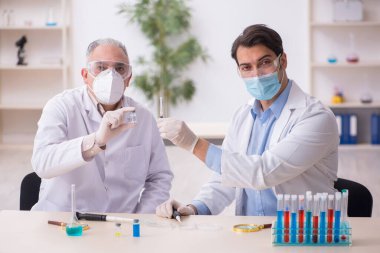 Salgın sırasında laboratuvarda çalışan iki erkek kimyager.