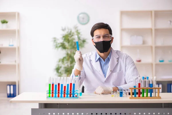 Jovem químico do sexo masculino que trabalha no laboratório durante a pandemia — Fotografia de Stock