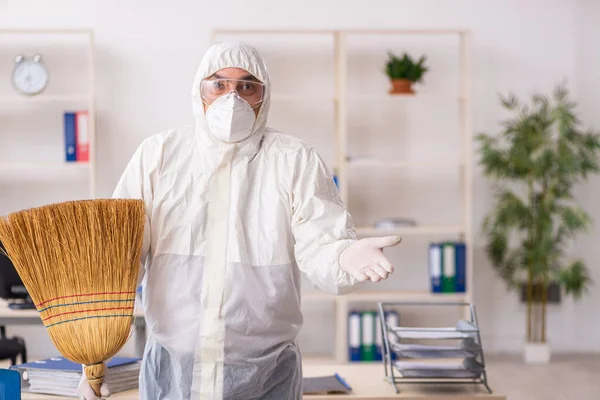 Empreiteiro velho limpando o escritório segurando vassoura — Fotografia de Stock