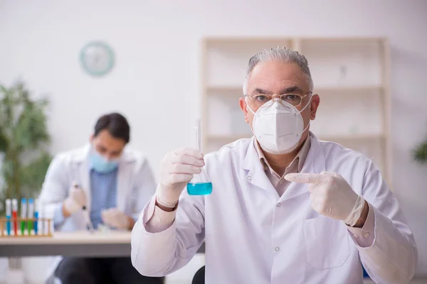 두 명의 남성 화학자가 전염병 이 유행하는 동안 실험실에서 일하고 있습니다. — 스톡 사진