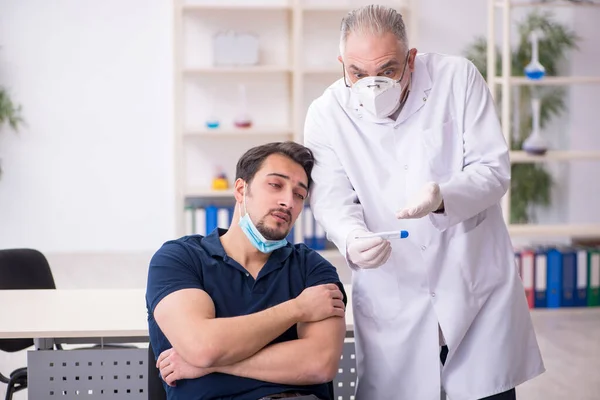 Genç erkek hasta yaşlı erkek doktoru aşıyla ziyaret ediyor. — Stok fotoğraf