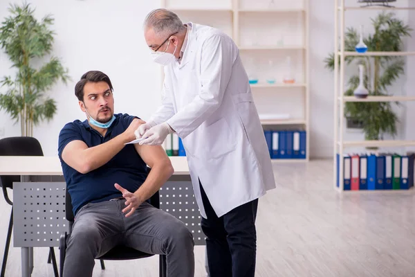Junge männliche Patientin besucht alten Arzt im Impfpass — Stockfoto