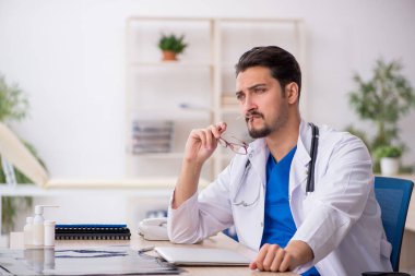 Klinikte çalışan genç erkek doktor.