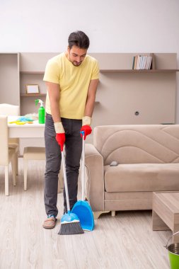 Genç erkek müteahhit evi temizliyor.