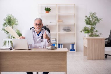 Klinikte çalışan yaşlı erkek doktor.