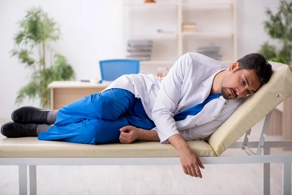 Stanco giovane medico maschio sdraiato sul divano in ospedale — Foto Stock