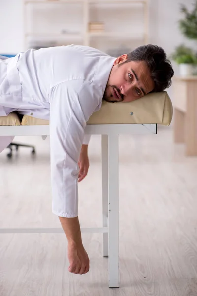 Cansado jovem médico deitado no sofá do hospital — Fotografia de Stock