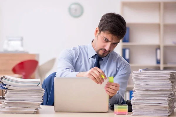 Joven empleado masculino y demasiado trabajo en la oficina — Foto de Stock